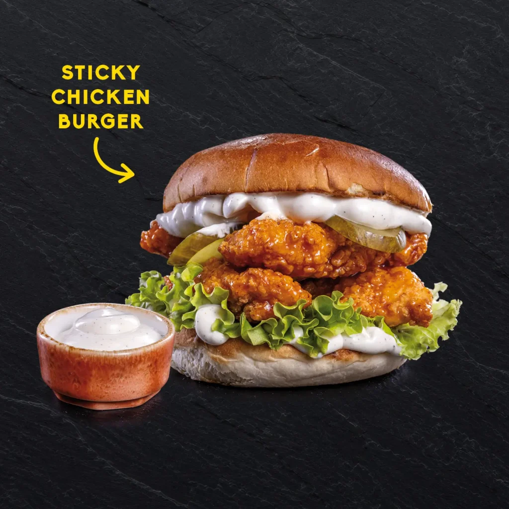 • Sticky Chicken Burger mit Hot Honey glasierten Crunchy Chicken Tenders, Gewürzgurken und Arizona Ranch